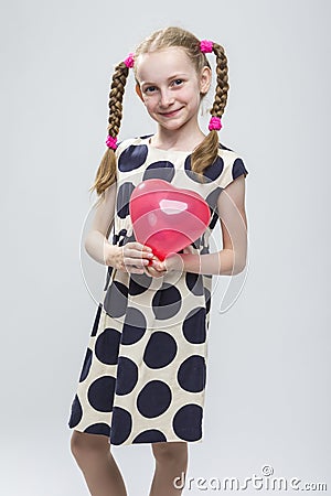 Caucasian Blond Girl With Pigtails Posing in Polka Dot Dress Against White. Stock Photo