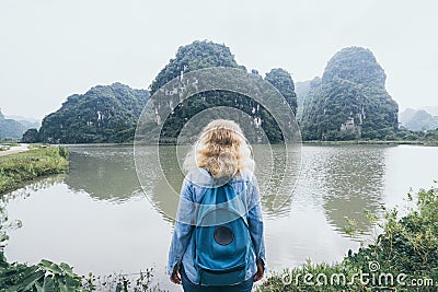 Caucasian blonde woman overlooking limestone mountains in Ninh Binh province, Vietnam Stock Photo