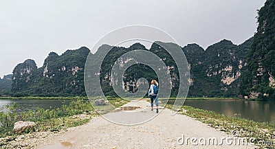 Caucasian blonde woman running towards limestone mountains in Ninh Binh province, Vietnam Stock Photo
