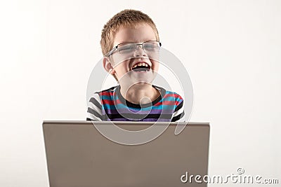 A Caucasian boy with glasses tries to work with a computer and the Internet. The guy gets vivid emotions Stock Photo