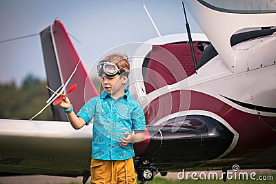 Caucasian boy in yellow shorts, a blue shirt and in aviation points holds the toy plane in hand and h Stock Photo