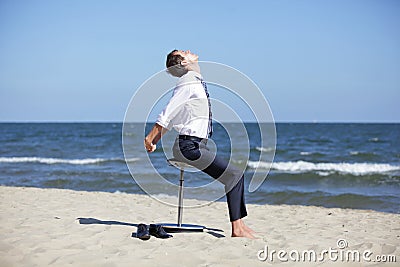 Caucasian business man stretching body on pneumatic stool on the beach Stock Photo