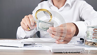 Caucasian businessman magnifying dollar banknotes Stock Photo