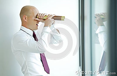 caucasian businessman spying using telescope thru office window Stock Photo