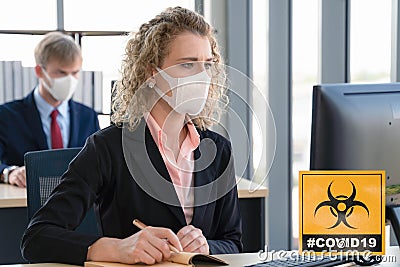 Caucasian businesspeople with medical mask for coronavirus covid 19 protection working in office with covid 19 sign Stock Photo
