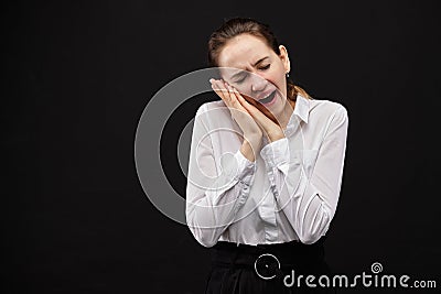 Caucasian businesswoman in a white shirt on a black background. A gesture depicting fatigue, drowsiness, desire to sleep Stock Photo