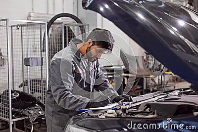 Concentrated auto mechanic man check the hood of car Stock Photo