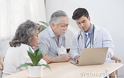 Caucasian doctor use laptop and talk with old asian male patient about disease symptom, elderly health check up at home Stock Photo