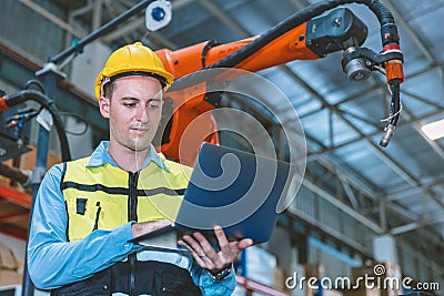 Caucasian engineer male worker working in metal factory with robot welding machine programmer controller and monitor Stock Photo