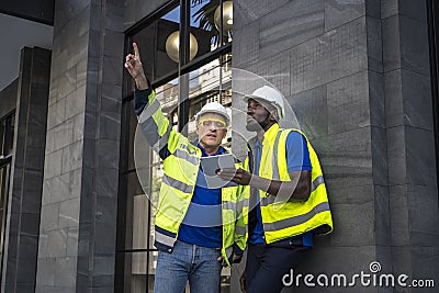 The caucasian engineer is pointing out the black engineers the destination they are discussing Stock Photo