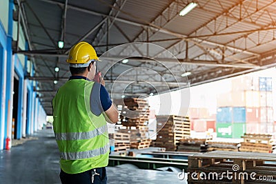 the caucasian engineer using walky talky comunicate with lifting container team with blue sky. Logistics transportation industry Stock Photo