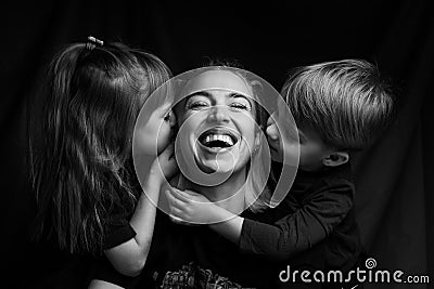 Caucasian Family Portrait in Black and White. mom daughter and son. mom laugh. son and daughter kiss mom on the cheeks Stock Photo