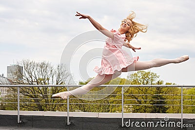 Caucasian fashion ballerina leaping on the roof Stock Photo