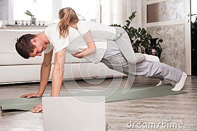 Caucasian father and small daughter in casual clothes do pushup pressup exercise on carpet on warm floor in living room, sporty Stock Photo