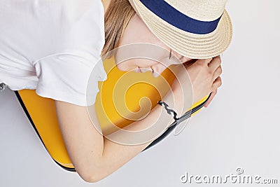 Caucasian girl teenager in a hat lies on a suitcase, tired of waiting. Vacation, summer vacation, travel Stock Photo