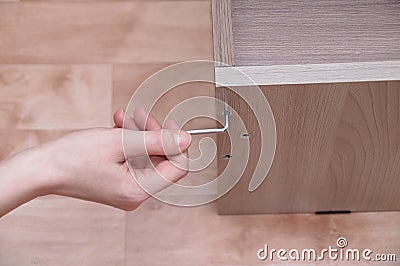 Caucasian girl tightens a screw with the key on the furniture. Close-up Stock Photo