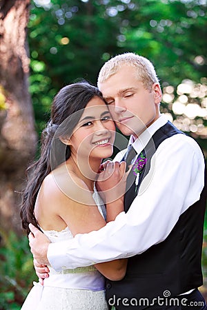 Caucasian groom holding his biracial bride, smiling. Diverse couple. Stock Photo