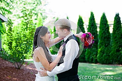 Caucasian groom holding his biracial bride, smiling. Diverse couple. Stock Photo