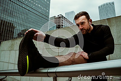 Caucasian male athlete stretching calves while running through city training for race Stock Photo