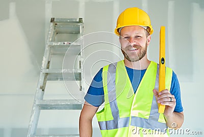 Caucasian Male Contractor With Hard Hat, Level and Safety Vest At Construction Site Stock Photo