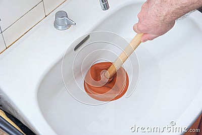 Caucasian male hand holding a plunger unclogging a bathroom sink Stock Photo