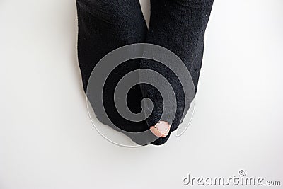 Caucasian male toe sticking out of worn out short nylon black plain socks with hole top view Stock Photo