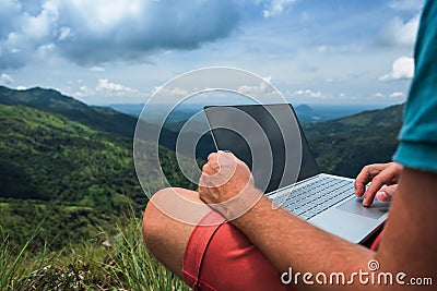 Caucasian man with laptop sitting on the edge of ella mountain with stunning views of the valley in Sri Lanka. Stock Photo