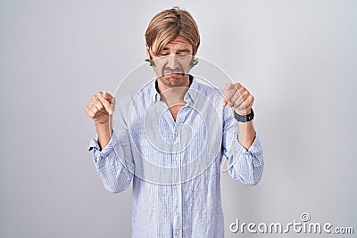 Caucasian man with mustache standing over white background pointing down looking sad and upset, indicating direction with fingers, Stock Photo