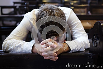 Caucasian man praying in church. He has problems and ask God for help Stock Photo