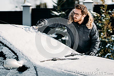 Caucasian man removes snow from vehicle, cleaning snow after blizzard Stock Photo