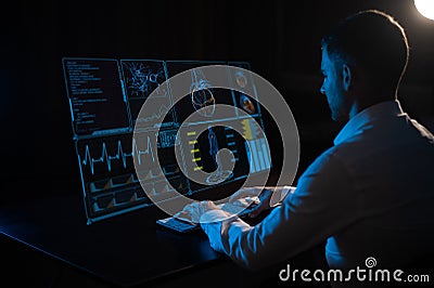 A caucasian man sits in the dark in front of a virtual menu and types on a keyboard. Readings on the life support Stock Photo