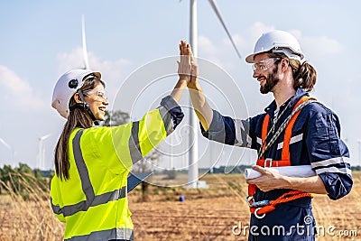 Caucasian man and woman engineers in uniform discuss with shaking hands stand near wind turbines ecological energy industry, Stock Photo