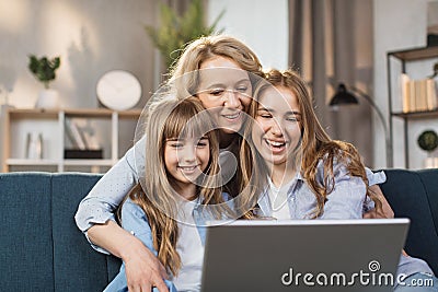 Caucasian mother and children sitting on couch using laptop, family enjoy distant talk by video call Stock Photo
