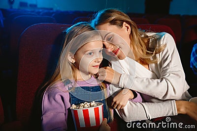 Young caucasian mother and daughter watching a film at a movie theater Stock Photo
