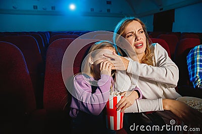 Young caucasian mother and daughter watching a film at a movie theater Stock Photo