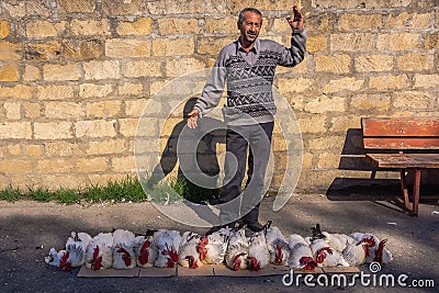 Caucasian mountaineer sells live roosters Editorial Stock Photo