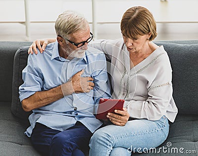 Caucasian old senior elderly unhealthy unwell gray hair and bearded husband sitting together with wife suffering from heart attack Stock Photo