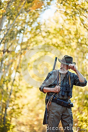 Hunter with shotgun in back stand in forest Stock Photo