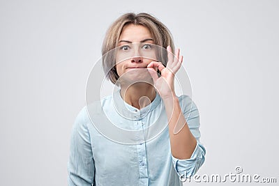 Caucasian pretty woman zipping her mouth shut Stock Photo