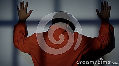 Caucasian prisoner standing near wall, security checkup in jail, incarceration Stock Photo