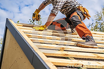 Roofing Contractor Attaching Wooden Elements to the House Roof Stock Photo