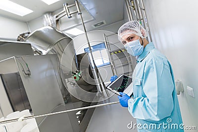 Scientist make notes about metal machine with barrels Stock Photo