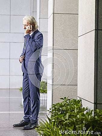 Caucasian senior executive talking on cellphone in lobby of mode Stock Photo