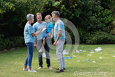 Caucasian senior couple with father and son in volunteer shirts talking in littered field Stock Photo