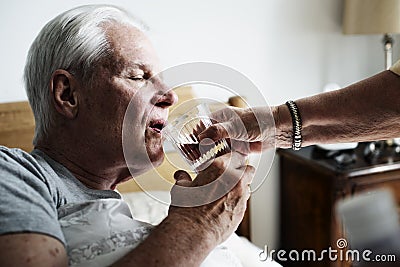 Caucasian senior man drinking water in his bed Stock Photo