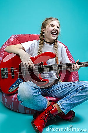 Expressive Caucasian Teenager Guitar Player With Red Shiny Bass Guitar Posing In Casual White Shirt With Smiling Facial Expression Stock Photo