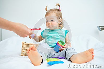 Caucasian toddler playing with multicolored toys with mom on bed Stock Photo