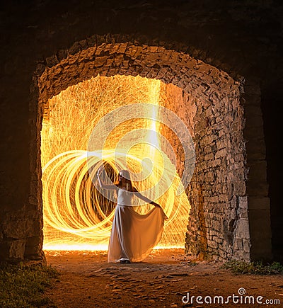 Caucasian white female model with long hair, in a white dress standing and throws gleaming sparks. Stock Photo
