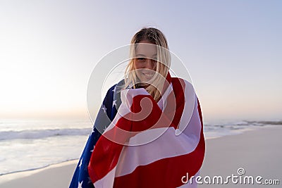 Caucasian woman covering herself with a US flag at the beach Stock Photo