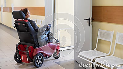Caucasian woman in electric wheelchair in hospital corridor. Stock Photo